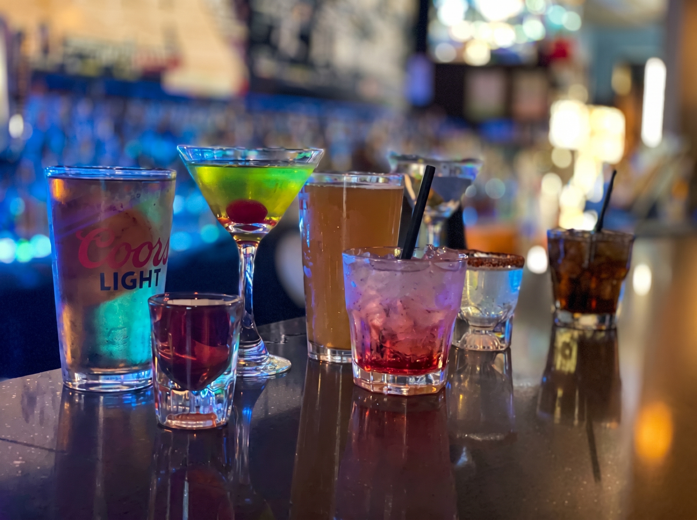 Coors Light pint, a green martini, cocktails and shots lined up on the bar at The Blue Moon